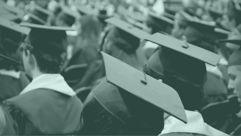 Graduates in caps and gowns facing away from camera.